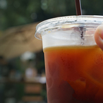 close-up of hand holding soft drink cup with lid and straw